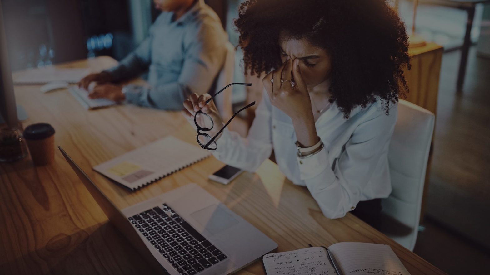 Woman pinching bridge of her nose and holding her glasses