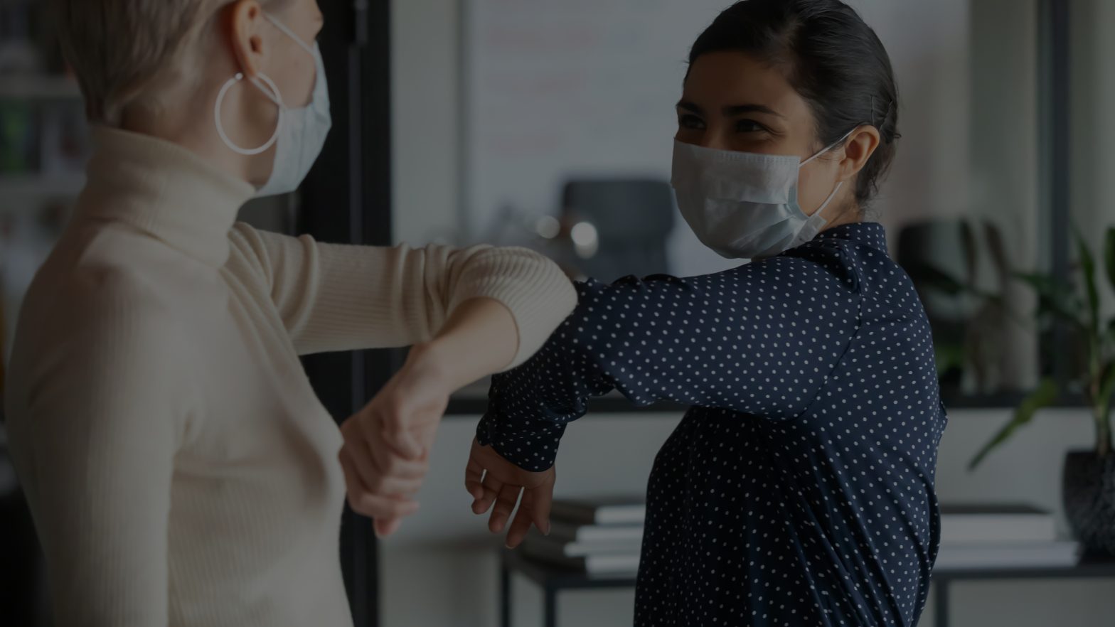 People wearing masks bumping elbows