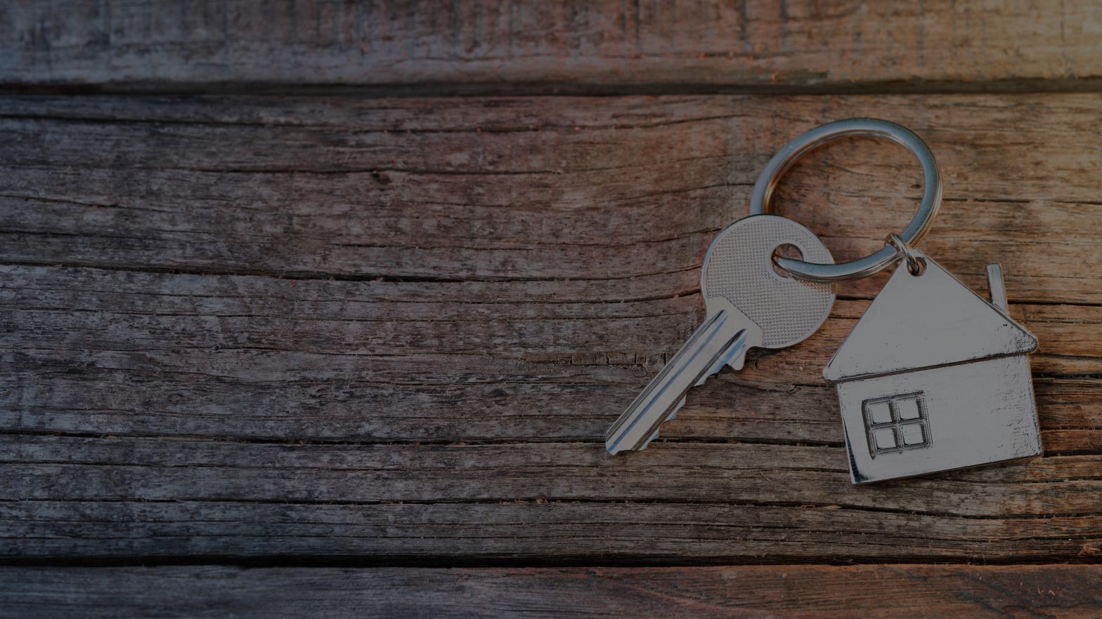 Single key on keywring with a house sat on wooden table